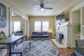 A living room with a sofa, a dining table, a fireplace, and a ceiling fan. - Yard, Fireplace, Full Kitchen! Oakland Home (Oakland)
