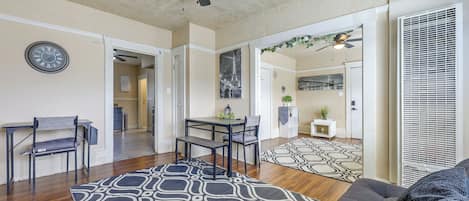 A spacious living area with a ceiling fan, a dining table with chairs, a patterned rug, and a sofa.
