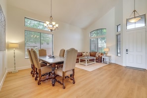 A spacious dining area with a wooden table and chairs, a chandelier, and large windows with blinds. - Fire Pit & Large Yard! Luxury Anthem Escape (Phoenix)