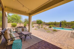 A covered patio area with outdoor furniture, a pool, and a view of the surrounding landscape. - Fire Pit & Large Yard! Luxury Anthem Escape (Phoenix)