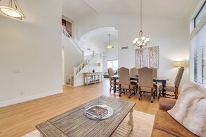 A spacious living room with a wooden coffee table, a dining area with a chandelier, and a staircase leading to an upper level. - Fire Pit & Large Yard! Luxury Anthem Escape (Phoenix)