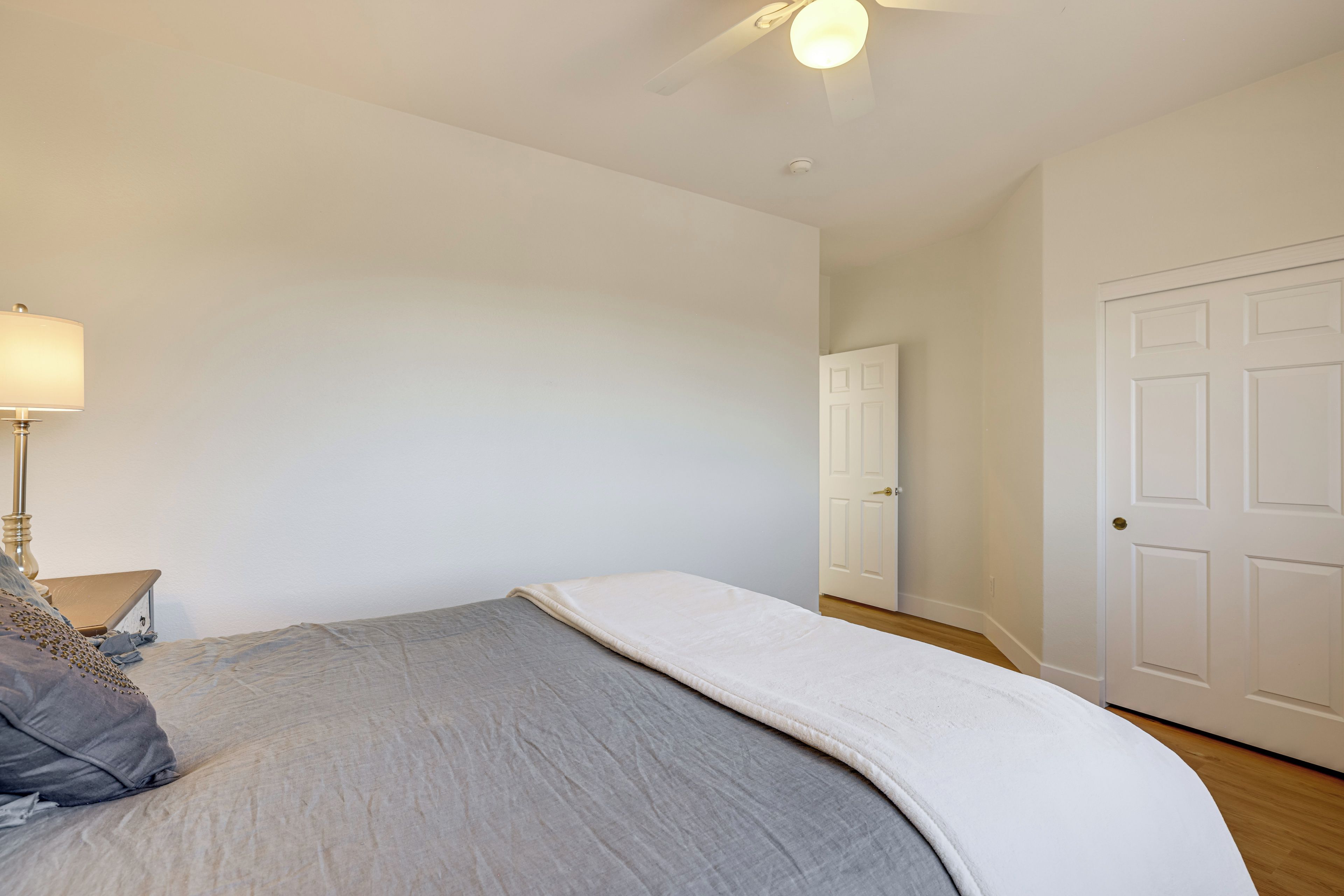 A bedroom with a bed, a nightstand with a lamp, and a door.