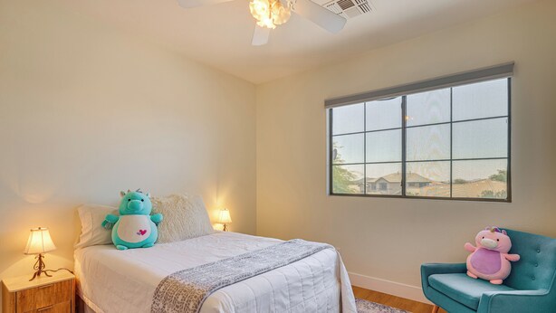 A bedroom with a bed, two nightstands, a window, and a chair.