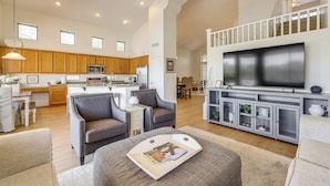 A spacious living area with a kitchen, dining area, and a large flat-screen TV.