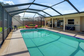 Ein überdachter Pool mit Liegefläche, inklusive Liegestühlen und Grill.