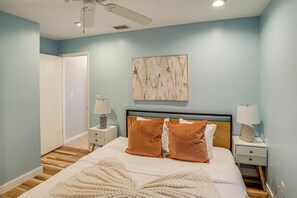 Ein Schlafzimmer mit Bett, Nachttischen, Deckenventilator und einem Wandbild.