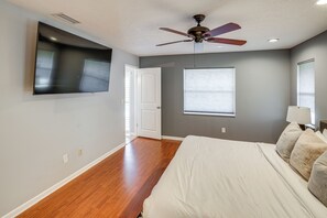 A bedroom with a bed, a ceiling fan, a TV mounted on the wall, and a window with blinds. - Quiet Home 1 Mi to Savannas Preserve State Park! (Port Saint Lucie)