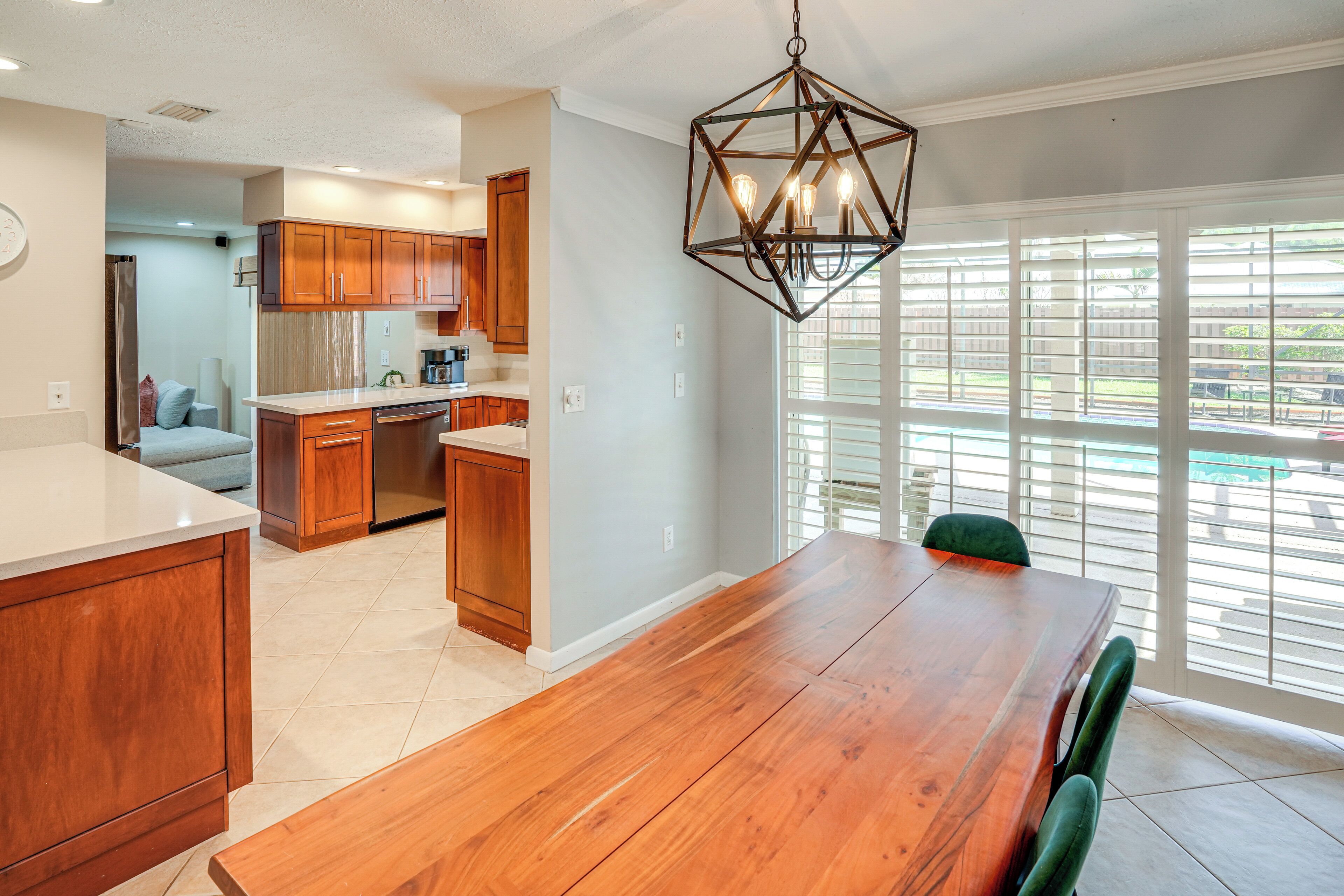 Una cocina moderna con armarios de madera, un refrigerador de acero inoxidable y una zona de comedor con una mesa y sillas de madera.