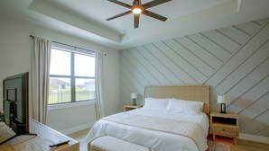 Ein Schlafzimmer mit einem Bett, Nachttischen, einem Fernseher und einem Deckenventilator.