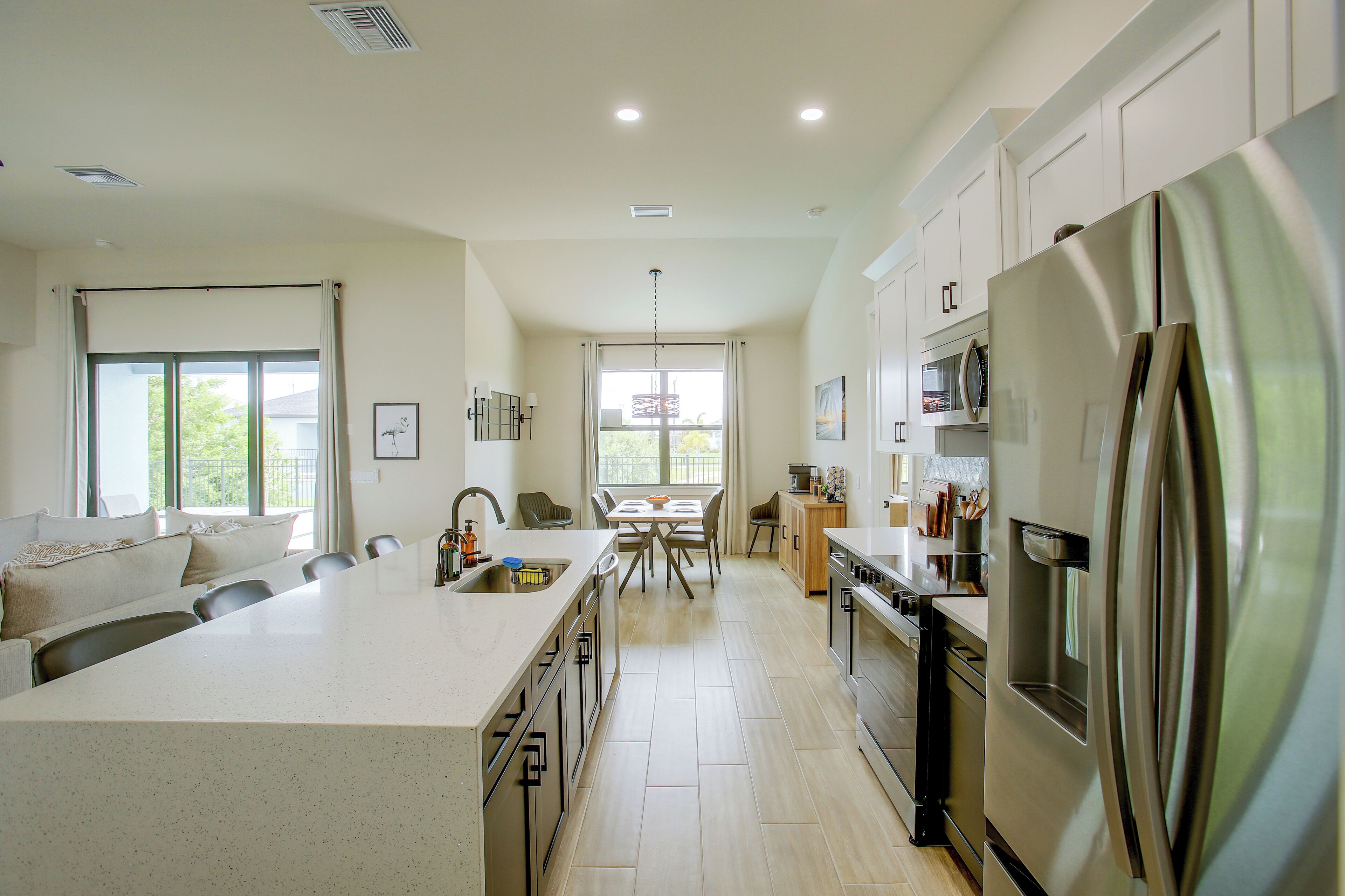 A modern kitchen with a central island, stainless steel appliances, and a dining area with a view.