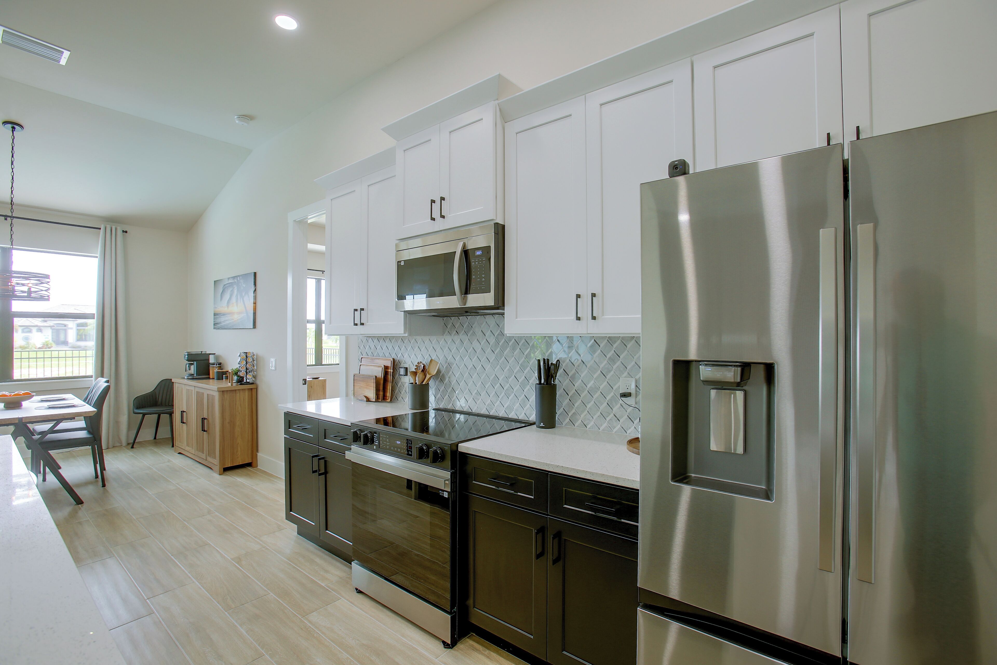 A modern kitchen with stainless steel appliances, wooden cabinets, and a dining area with a view.