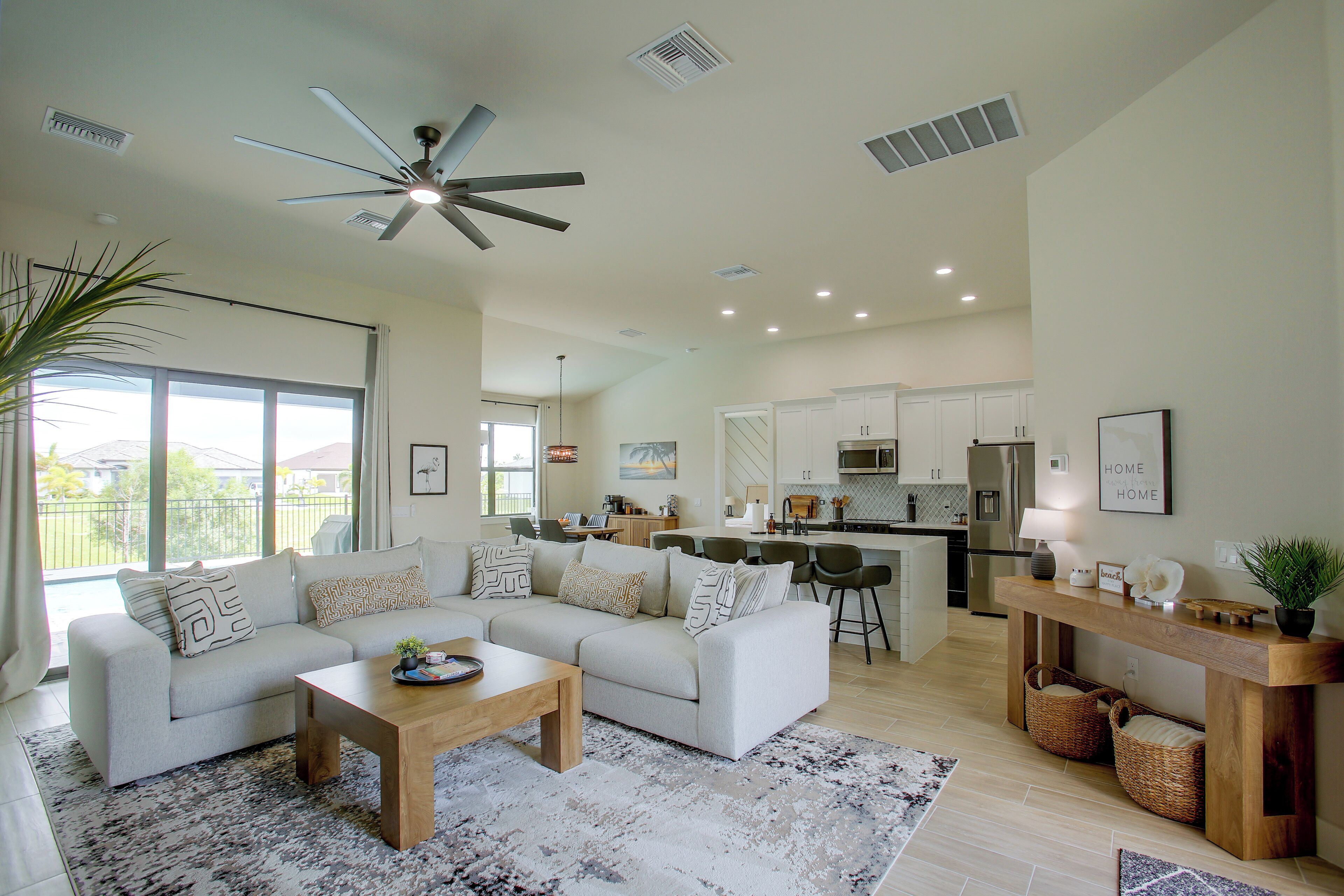 A spacious living room with a large sofa, a coffee table, and a view of the kitchen and outdoor area.