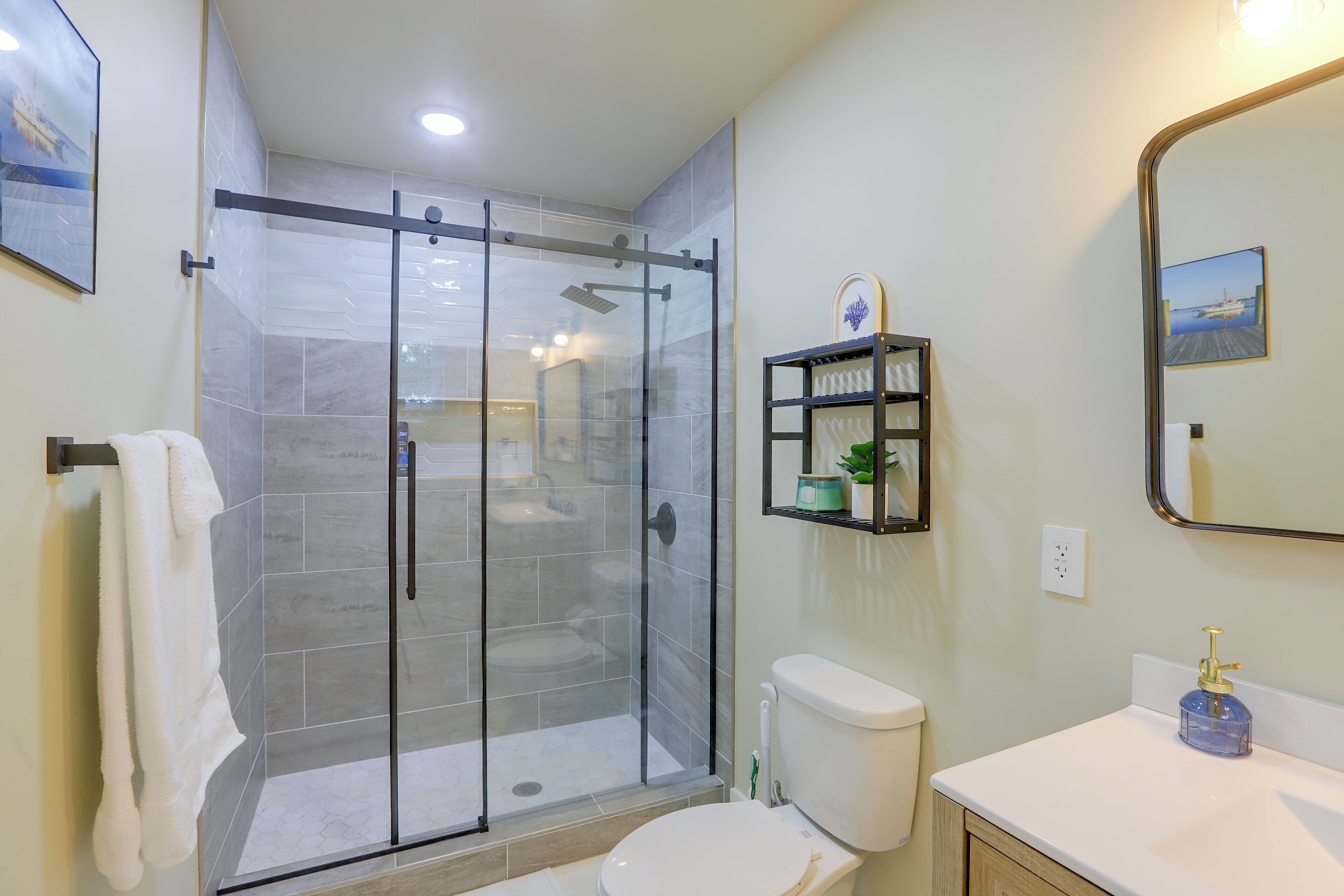 A modern bathroom with a glass-enclosed shower, a toilet, a sink, and a mirror.