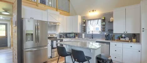 A modern kitchen with a central island, stainless steel appliances, and a wooden upper deck.