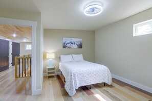 Ein Schlafzimmer mit einem Bett, einem Nachttisch, einer Lampe, einem Bild und einem Deckenventilator.