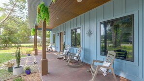 A covered porch with rocking chairs and potted plants. - Blue Heron - New Modern Home in Carrabelle (Carrabelle)