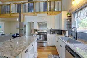 Eine moderne Küche mit Granit-Arbeitsplatten, Edelstahlgeräten und einer Holzzieldecke.