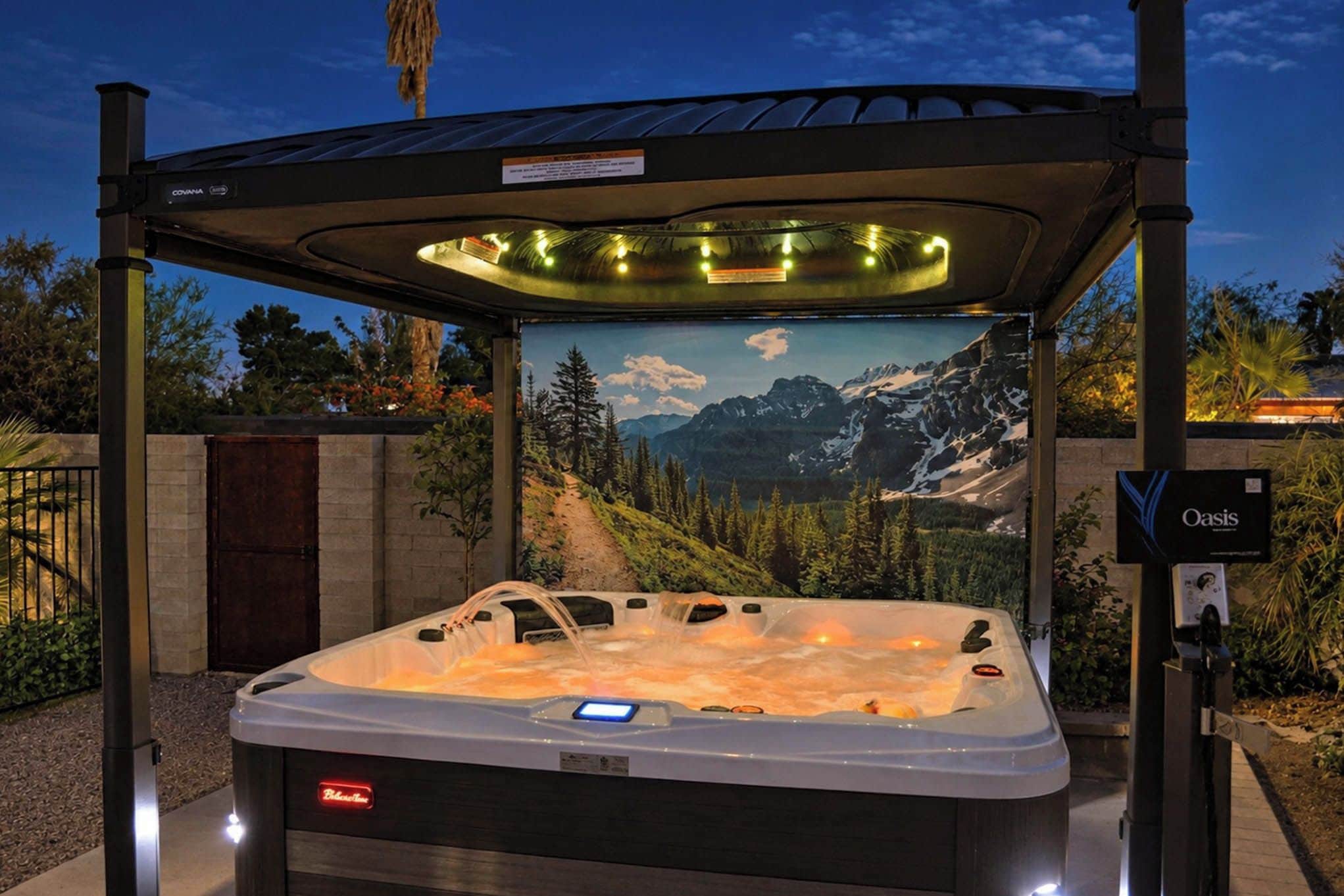 Un bain à remous doté d’un panneau de commande numérique, entouré d’une structure métallique, avec un paysage montagneux en toile de fond.