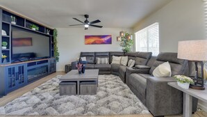 A modern living room with a sectional sofa, a flat-screen TV, a ceiling fan, and a decorative plant. - Private Pool Retreat Near Tucson Attractions (Tucson)