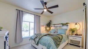 A bedroom with a bed, a ceiling fan, a bedside table with a lamp, a window with curtains, and a plant. - Private Pool Retreat Near Tucson Attractions (Tucson)