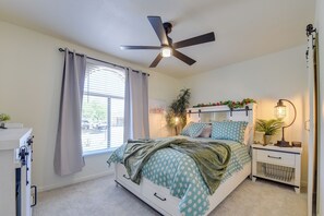 A bedroom with a bed, a ceiling fan, a bedside table with a lamp, a window with curtains, and a plant. - Private Pool Retreat Near Tucson Attractions (Tucson)