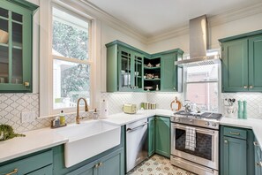 A kitchen with green cabinets, a white countertop, a stainless steel stove, and a window with a view of greenery. - 1 Mi to Dtwn Tyler! Historic Retreat + Guest Suite (Tyler)
