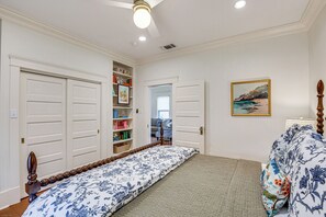 Ein Schlafzimmer mit einem Bett, einem Bücherregal, einem Gemälde und einer Tür zu einem anderen Raum.