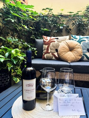 A bottle of wine, two glasses, and a thank you note on a table with a woven placemat. - Bella Vigna (Florence)