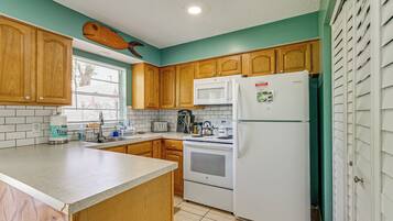A kitchen with wooden cabinets, a white refrigerator, a microwave, and a stove.