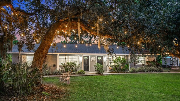 A house with a well-maintained lawn, a large tree with hanging lights, and a front door with a circular window. - Bring Your Boat! Retreat 5 Mi to Crystal River (Homosassa)