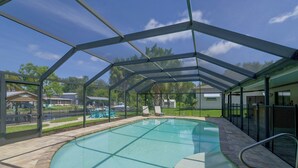 Ein überdachter Pool mit freiem Blick auf die Umgebung, darunter eine Rasenfläche und ein Gebäude im Hintergrund.