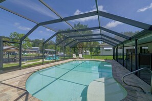 Ein überdachter Pool mit freiem Blick auf die Umgebung, darunter eine Rasenfläche und ein Gebäude im Hintergrund.