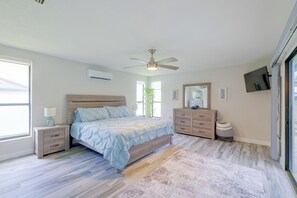Ein Schlafzimmer mit einem Bett, Nachttischen, einer Kommode, einem Deckenventilator und einem Fernseher.