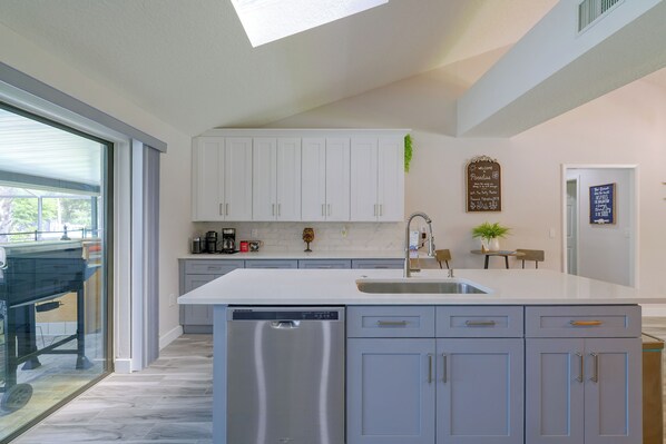 A modern kitchen with a dishwasher, a sink, and a large island with drawers. - Canal-front Crystal River Home w/ Boat Dock (Crystal River)