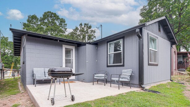 A single-story house with a patio area featuring a grill, two chairs, and a small table. - Honey Creek Cabin on Grand Lake w/ Private Dock! (Grove)