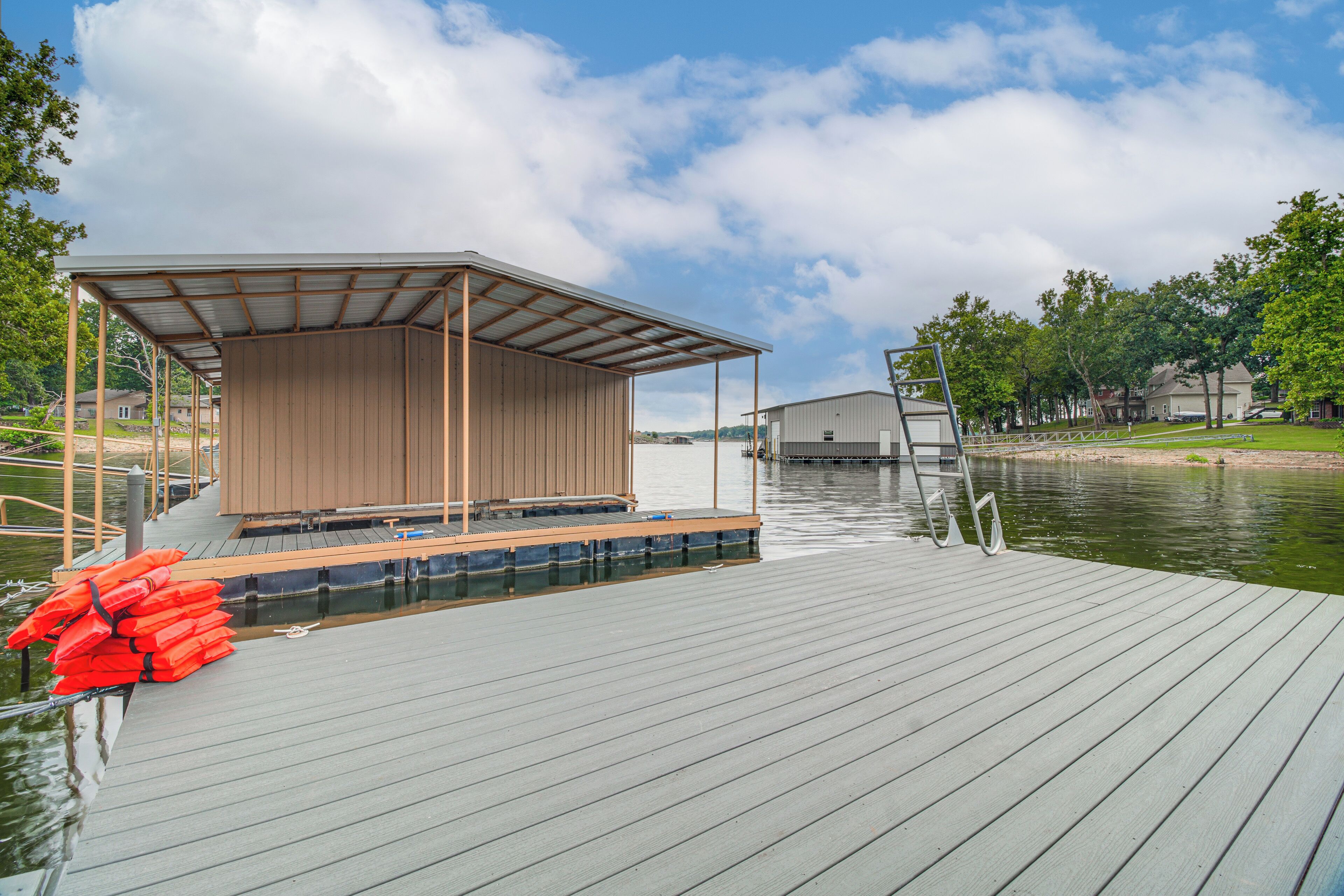 A wooden dock with a covered seating area and life jackets.