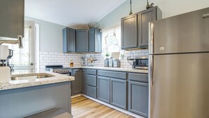 A modern kitchen with grey cabinets, stainless steel appliances, and a wooden floor. - Honey Creek Cabin on Grand Lake w/ Private Dock! (Grove)
