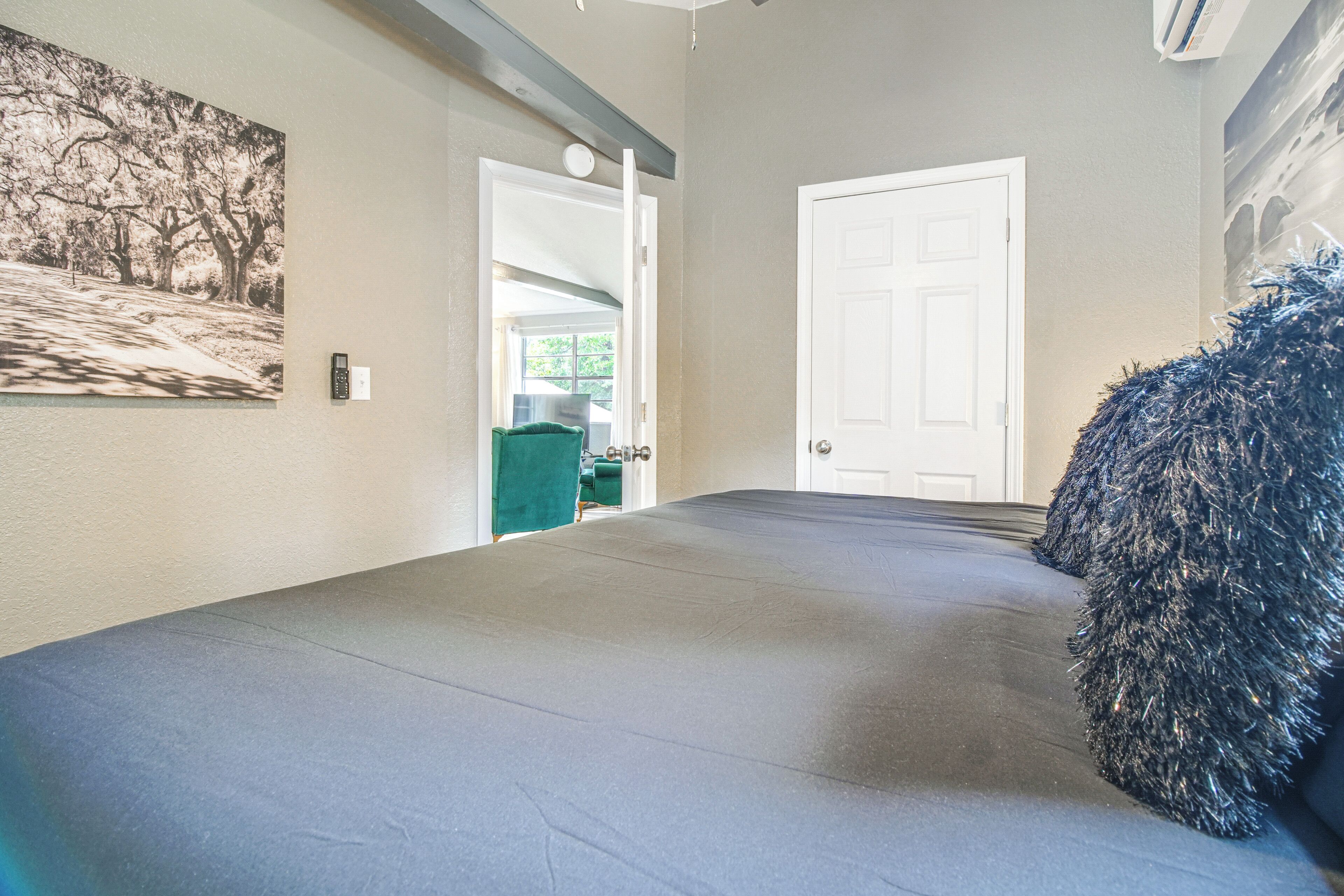 A hallway with a grey carpet, a door, a green chair, and a wall-mounted security device.