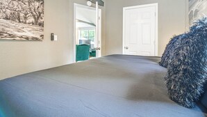 A hallway with a grey carpet, a door, a green chair, and a wall-mounted security device. - Honey Creek Cabin on Grand Lake w/ Private Dock! (Grove)