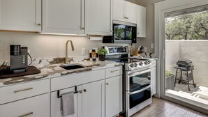 A modern kitchen with white cabinets, a built-in microwave, a gas stove, and an oven. - Hot Tub & Fire Pit! Texas Wine Country Retreat (Fredericksburg)