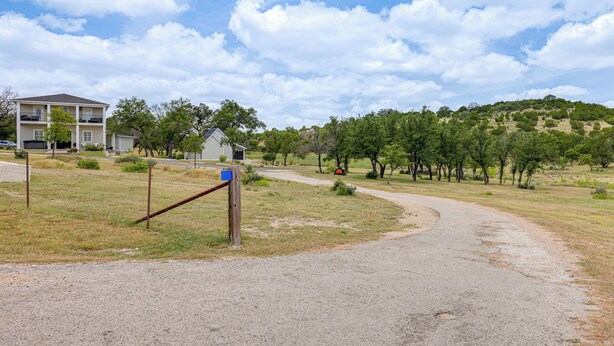 A gravel path leading to a building with a fenced entrance. - Hot Tub & Fire Pit! Texas Wine Country Retreat (Fredericksburg)