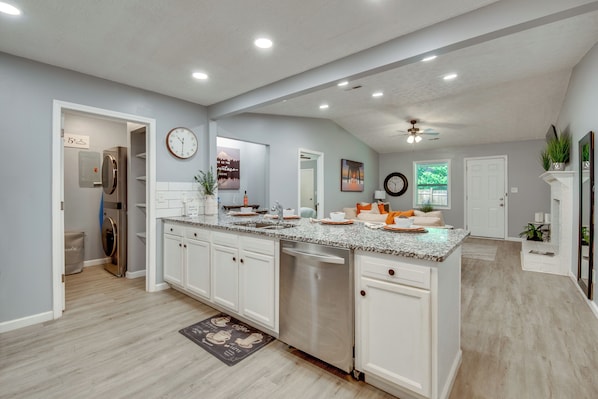 A spacious kitchen with a central island, built-in appliances, and a large clock on the wall.