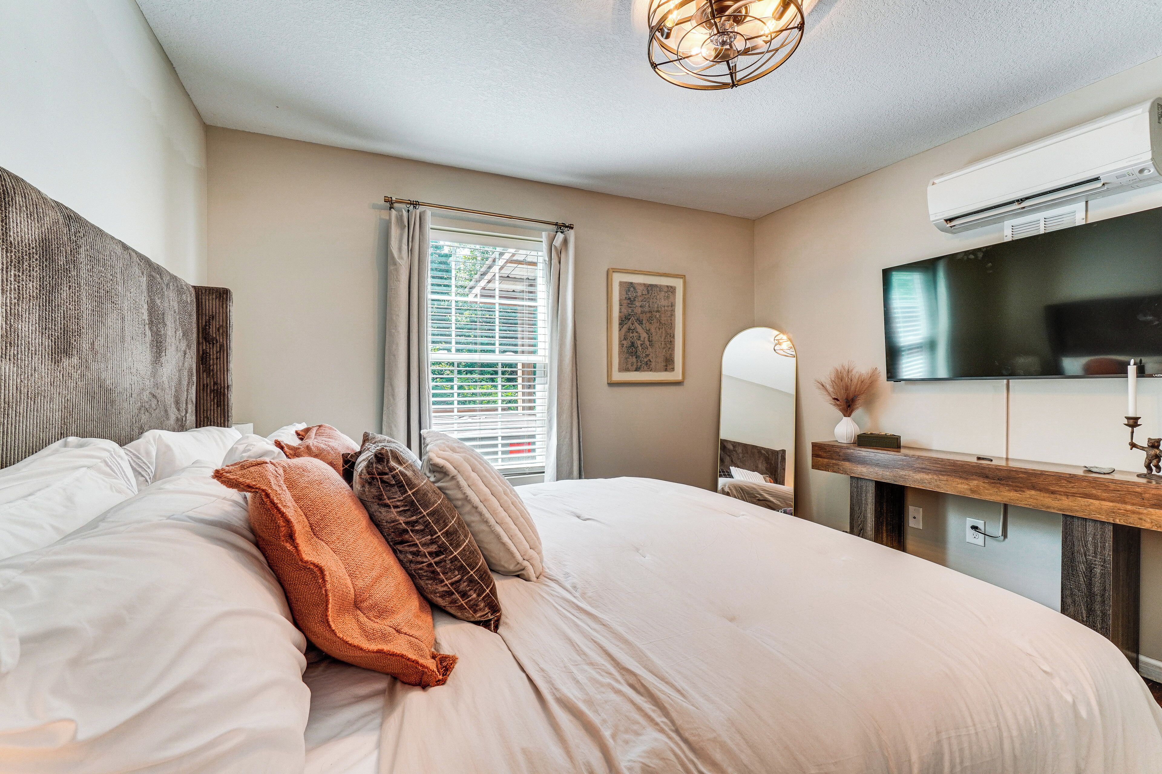 Une chambre d’hôtel avec un grand lit, une télévision, un miroir et une fenêtre avec des stores.