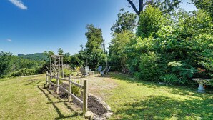 Een tuin met een houten klimconstructie, buitenterras en verschillende planten.