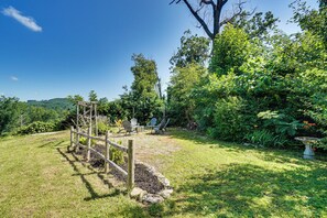 Ein Garten mit einer hölzernen Kletterkonstruktion, Sitzgelegenheiten im Freien und verschiedenen Pflanzen.