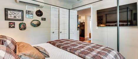 Un dormitorio con cama, televisor de pantalla plana y obras de arte colgadas en la pared.