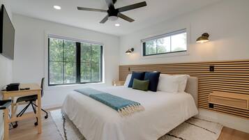 Un dormitorio moderno con una cama grande, un escritorio y un ventilador de techo.