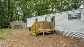 A mobile home with a wooden deck and a small staircase leading to a door.