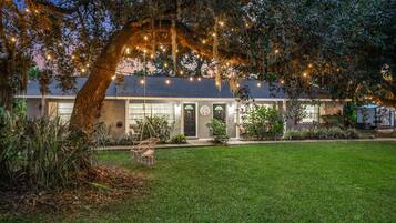 A house with a large front yard, a swing chair, and string lights.