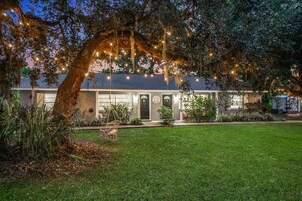 A house with a large front yard, a swing chair, and string lights.